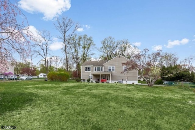 rear view of property with fence and a yard