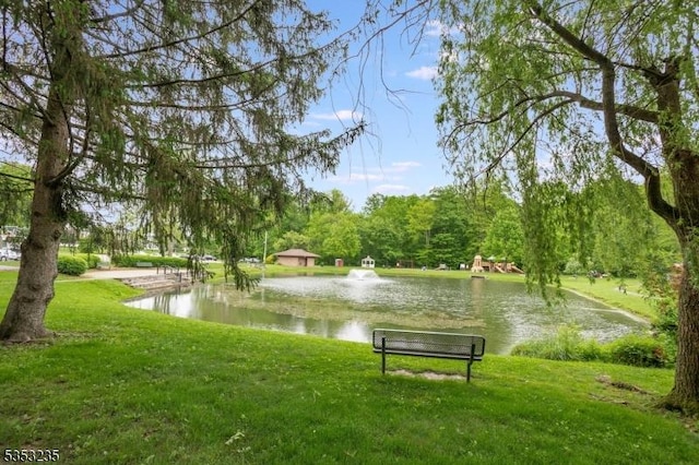 view of property's community with a water view and a lawn