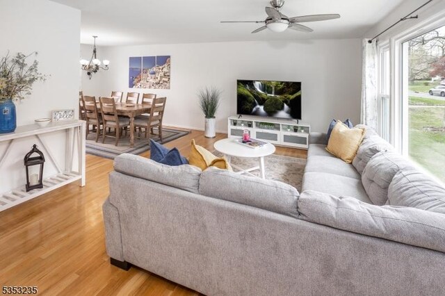 living room with light wood-type flooring and ceiling fan with notable chandelier