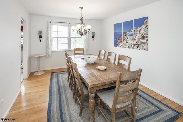 dining room featuring a notable chandelier, baseboards, and light wood-style floors