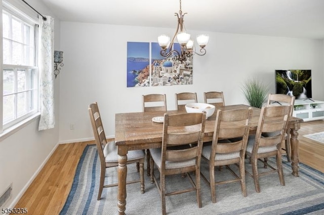 dining space featuring an inviting chandelier, a wealth of natural light, light wood-type flooring, and baseboards