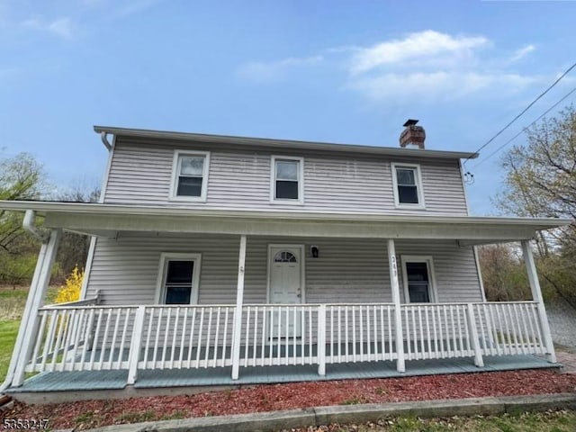 farmhouse inspired home featuring a porch and a chimney