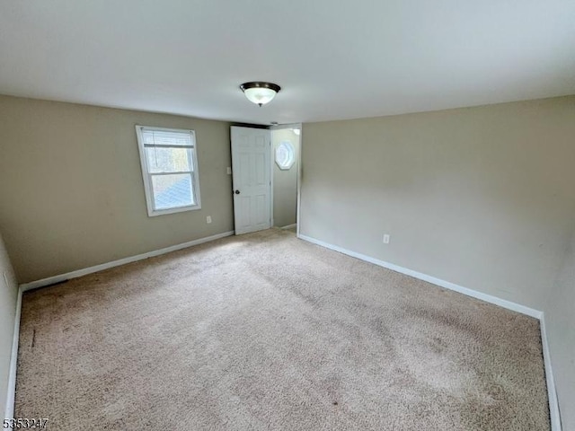 carpeted empty room featuring baseboards