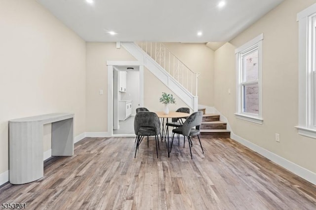 dining area with recessed lighting, baseboards, wood finished floors, and stairway
