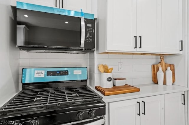 kitchen featuring light countertops, white cabinetry, decorative backsplash, and gas range