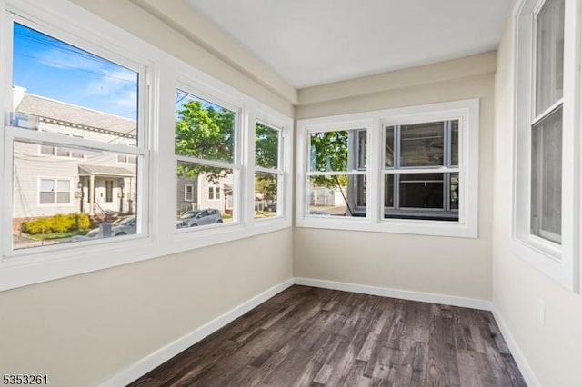 unfurnished sunroom with baseboards, wood finished floors, and a wealth of natural light