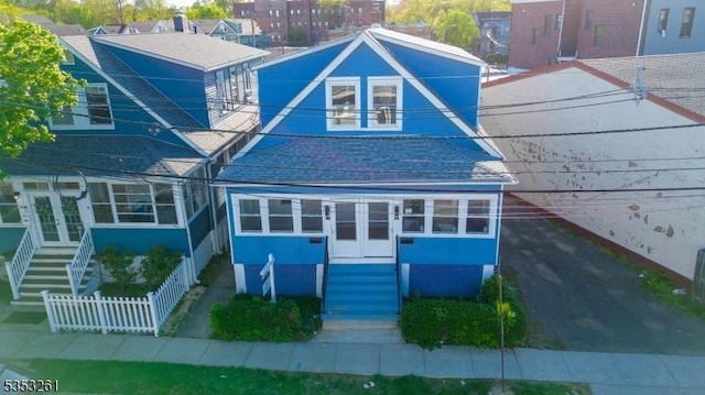 view of front of home featuring stairway, fence, french doors, and roof with shingles