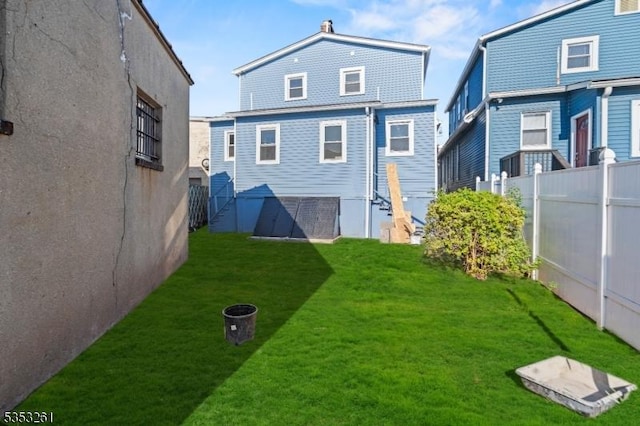 rear view of house featuring fence and a yard