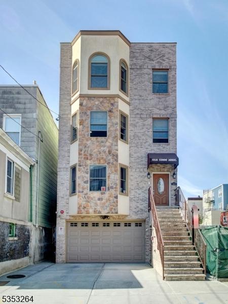 517 19th St, Union City, NJ 07087 - view of front facade with stone siding, an attached garage, and driveway