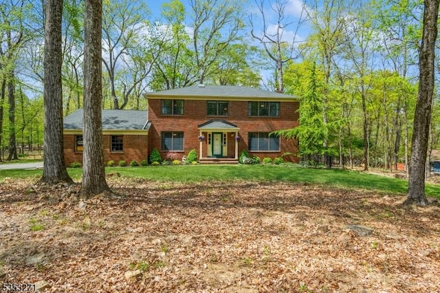 colonial house featuring brick siding and a front lawn