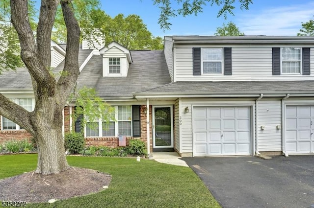 view of front of property with a front lawn, asphalt driveway, brick siding, and a garage