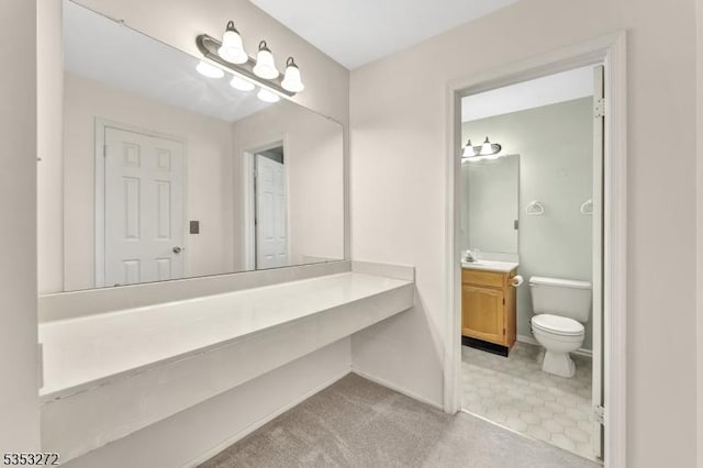 bathroom with toilet, vanity, and baseboards
