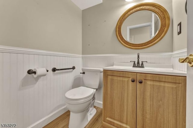 bathroom with wainscoting, toilet, wood finished floors, and vanity