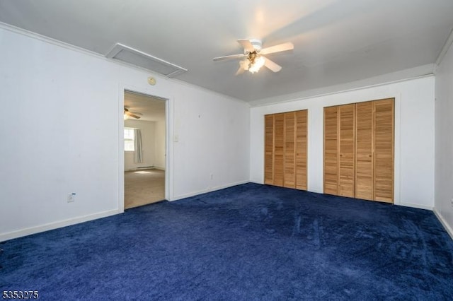 unfurnished bedroom featuring multiple closets, carpet, a ceiling fan, baseboards, and attic access
