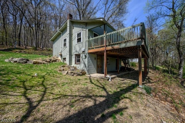 back of property featuring a chimney, a deck, a yard, and a carport