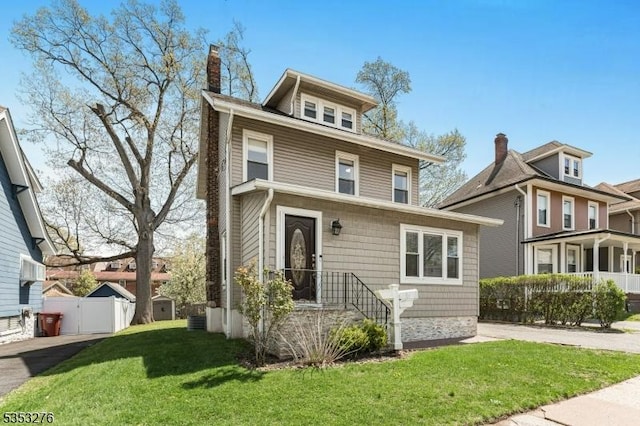 traditional style home featuring a front lawn, fence, and a chimney