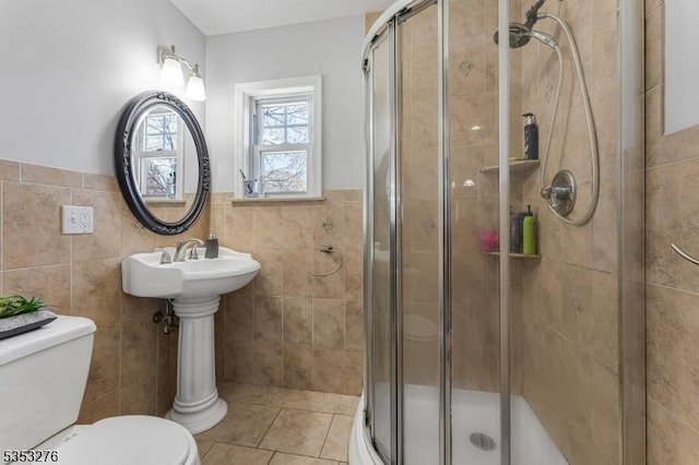 bathroom with wainscoting, tile patterned floors, a shower stall, and toilet