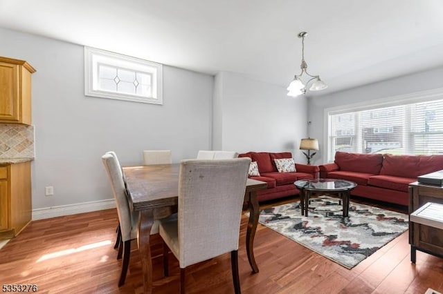 dining room with baseboards, an inviting chandelier, and light wood-style flooring