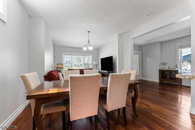 dining area featuring dark wood-style flooring, baseboards, a notable chandelier, and a wealth of natural light