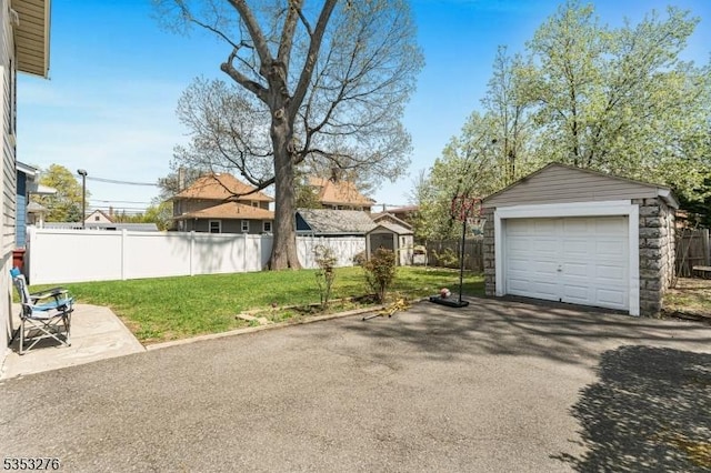 detached garage with fence and aphalt driveway