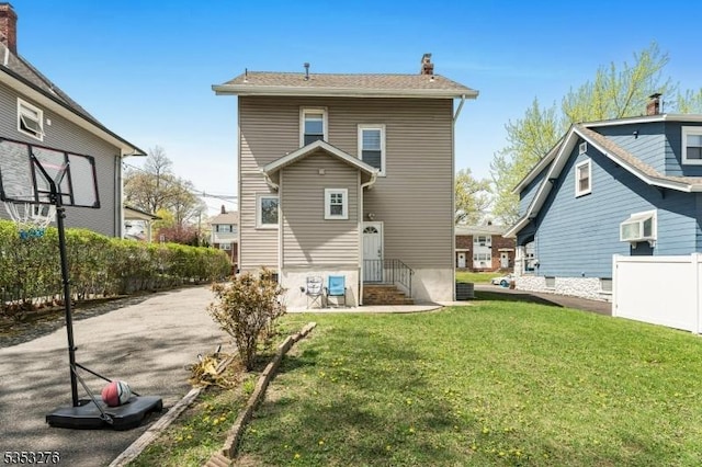 back of house featuring a lawn, fence, a chimney, and entry steps