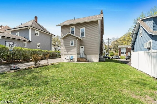 rear view of property with a chimney, a patio area, fence, a yard, and entry steps