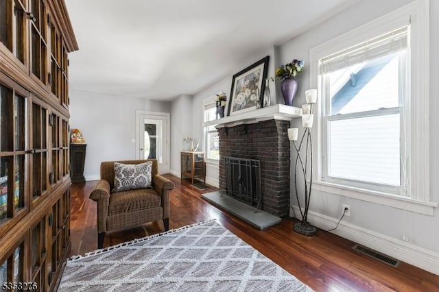 living area with visible vents, baseboards, wood finished floors, and a healthy amount of sunlight