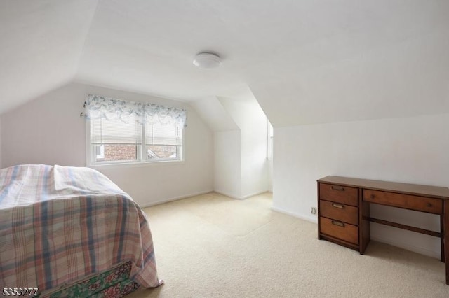 bedroom featuring light colored carpet, baseboards, and lofted ceiling
