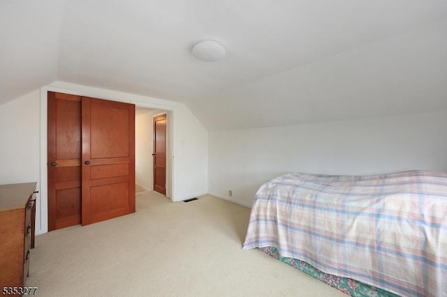 bedroom with visible vents, vaulted ceiling, and light colored carpet