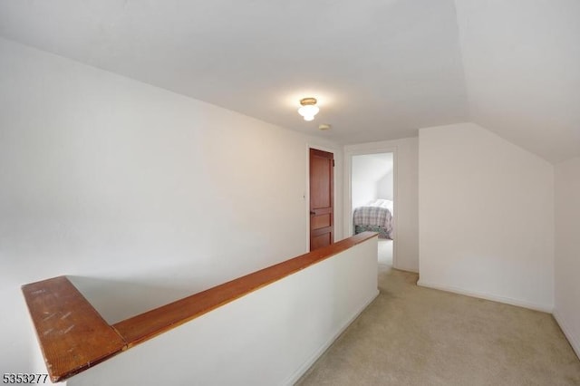 corridor featuring light colored carpet and lofted ceiling