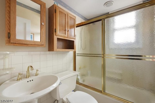 full bathroom with a sink, toilet, enclosed tub / shower combo, tile walls, and tasteful backsplash