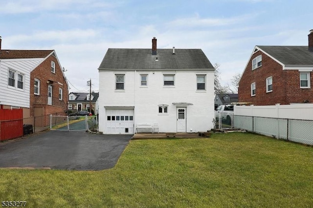 rear view of property featuring driveway, a chimney, a lawn, fence, and an attached garage