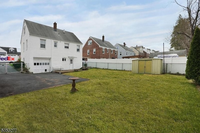 rear view of property featuring a garage, a chimney, a storage unit, driveway, and a residential view
