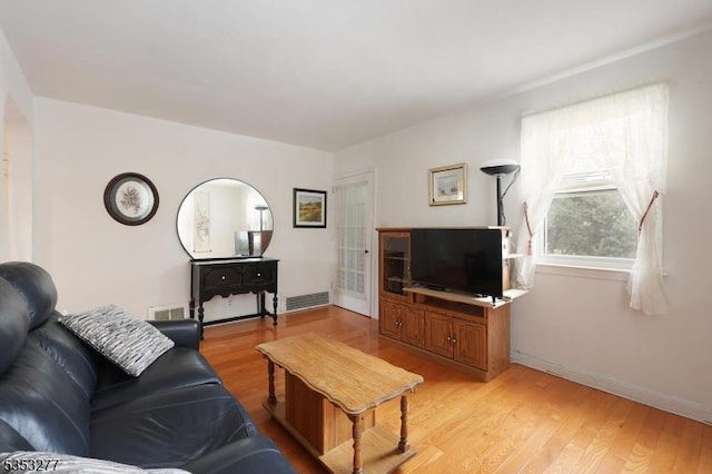 living area featuring baseboards, light wood finished floors, and visible vents
