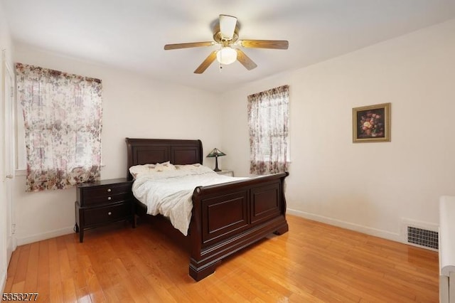 bedroom featuring baseboards, visible vents, ceiling fan, and light wood finished floors