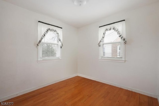 unfurnished room with baseboards and light wood-style floors