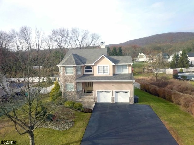 traditional-style home with a front lawn, a garage, stone siding, aphalt driveway, and stucco siding