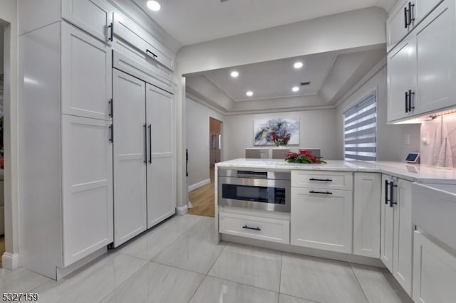 kitchen featuring white cabinetry, a peninsula, recessed lighting, and a tray ceiling
