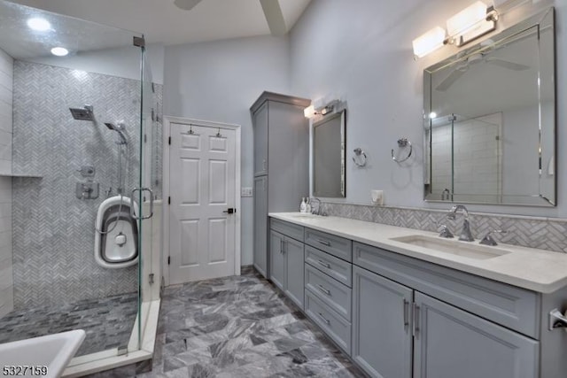 full bathroom featuring tasteful backsplash, a shower stall, double vanity, and a sink