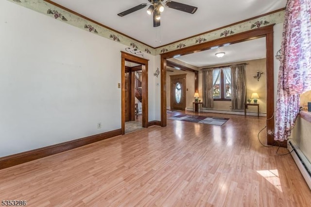 foyer entrance with baseboard heating, light wood-style flooring, a ceiling fan, baseboards, and ornamental molding