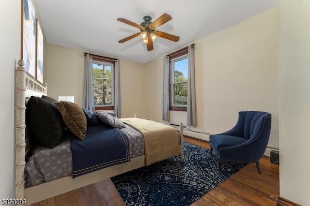 bedroom featuring a ceiling fan, a baseboard heating unit, and wood finished floors