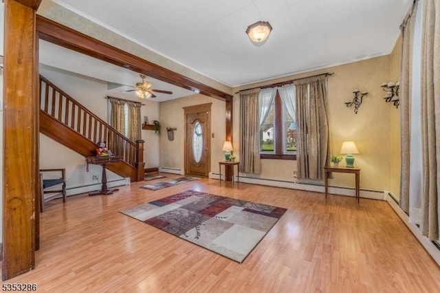 foyer entrance featuring stairs, baseboards, a baseboard heating unit, and wood finished floors