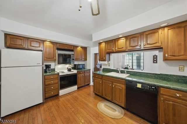 kitchen featuring brown cabinetry, black appliances, dark countertops, and a sink