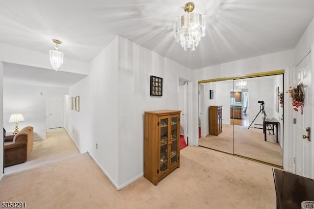 corridor featuring an inviting chandelier, baseboards, and light carpet
