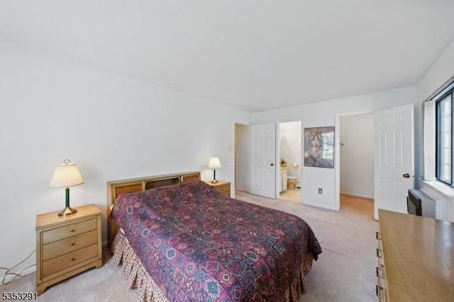 bedroom with ensuite bathroom and light carpet