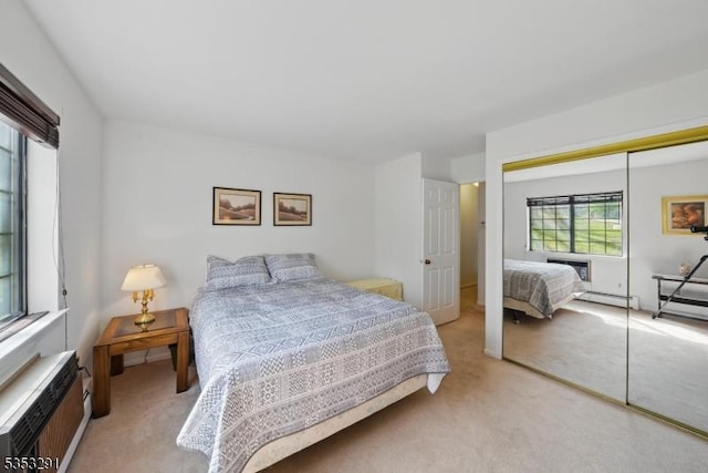 bedroom featuring a baseboard heating unit, a closet, light colored carpet, and a wall mounted AC