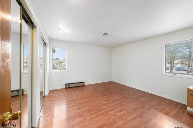 1250 N Broad St Unit A1, Hillside Twp, NJ 07205 - unfurnished bedroom featuring visible vents, multiple windows, light wood-style flooring, and a baseboard radiator