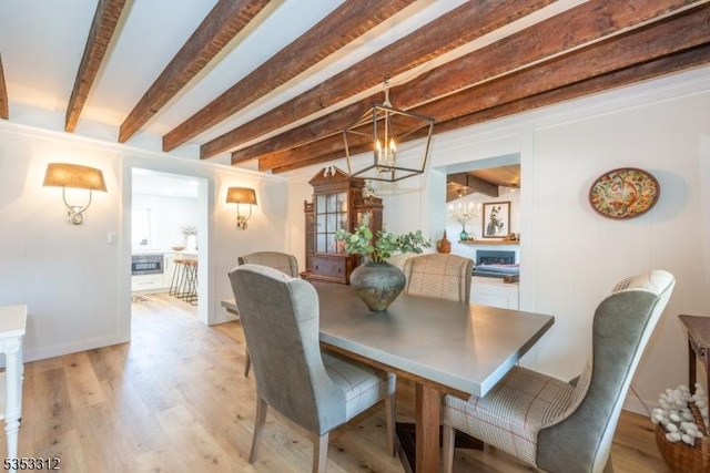 dining space featuring beam ceiling and light wood-type flooring