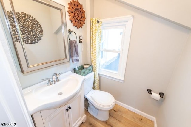 bathroom with toilet, wood finished floors, vanity, and baseboards