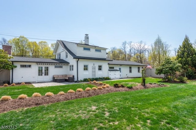 rear view of house featuring a chimney, french doors, outdoor lounge area, and a yard